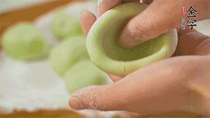 將均分的艾草面團(tuán)搓成圓，挖一個(gè)窩，放入餡心，再搓成圓。