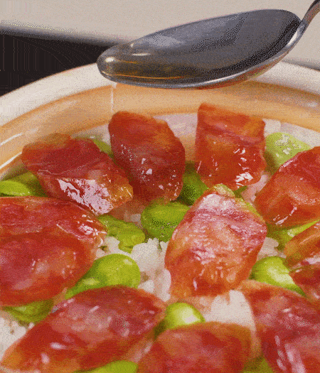 大米出現(xiàn)小孔時開蓋放香腸，往鍋邊淋入少許油，再燜煮8~10分鐘左右。