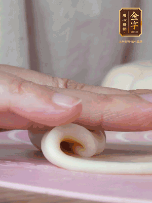 做面劑 油皮按扁，中間包入一個(gè)油酥，邊緣收緊捏死。包好的面劑按扁，用搟面杖搟壓成橢圓形。從底部向上卷成筒狀，用保鮮膜蓋好松弛15分鐘，再把筒狀縱向搟壓成長(zhǎng)條狀。再卷一次，松弛20分鐘